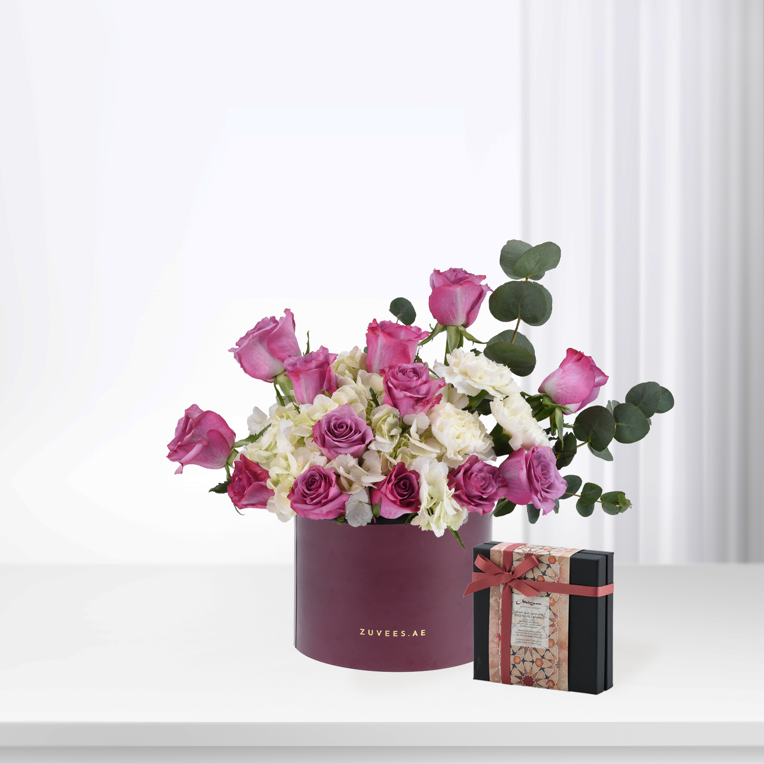Elegant pink roses, white hydrangeas in burgundy Zuvees box, paired with patterned gift box, soft light.