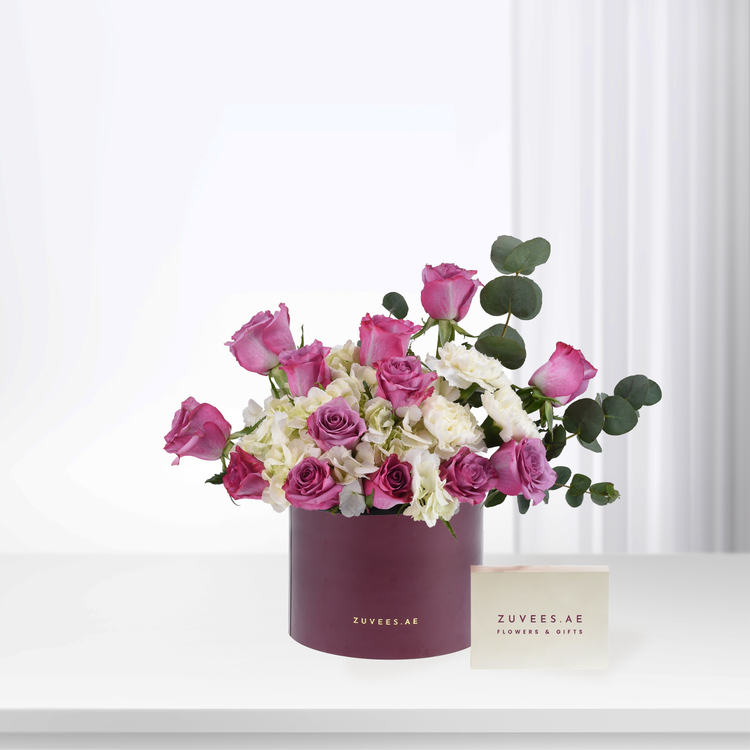Elegant burgundy box holds vibrant pink roses, white hydrangeas, and eucalyptus.