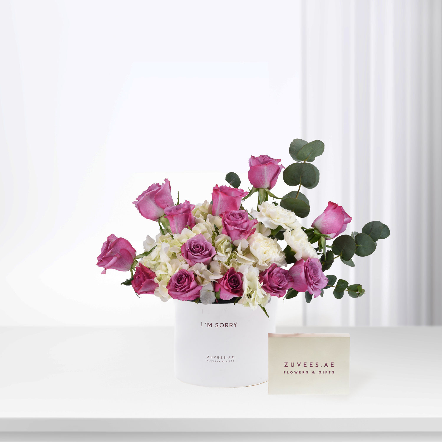 Pink roses and white hydrangeas in white box reading “I&
