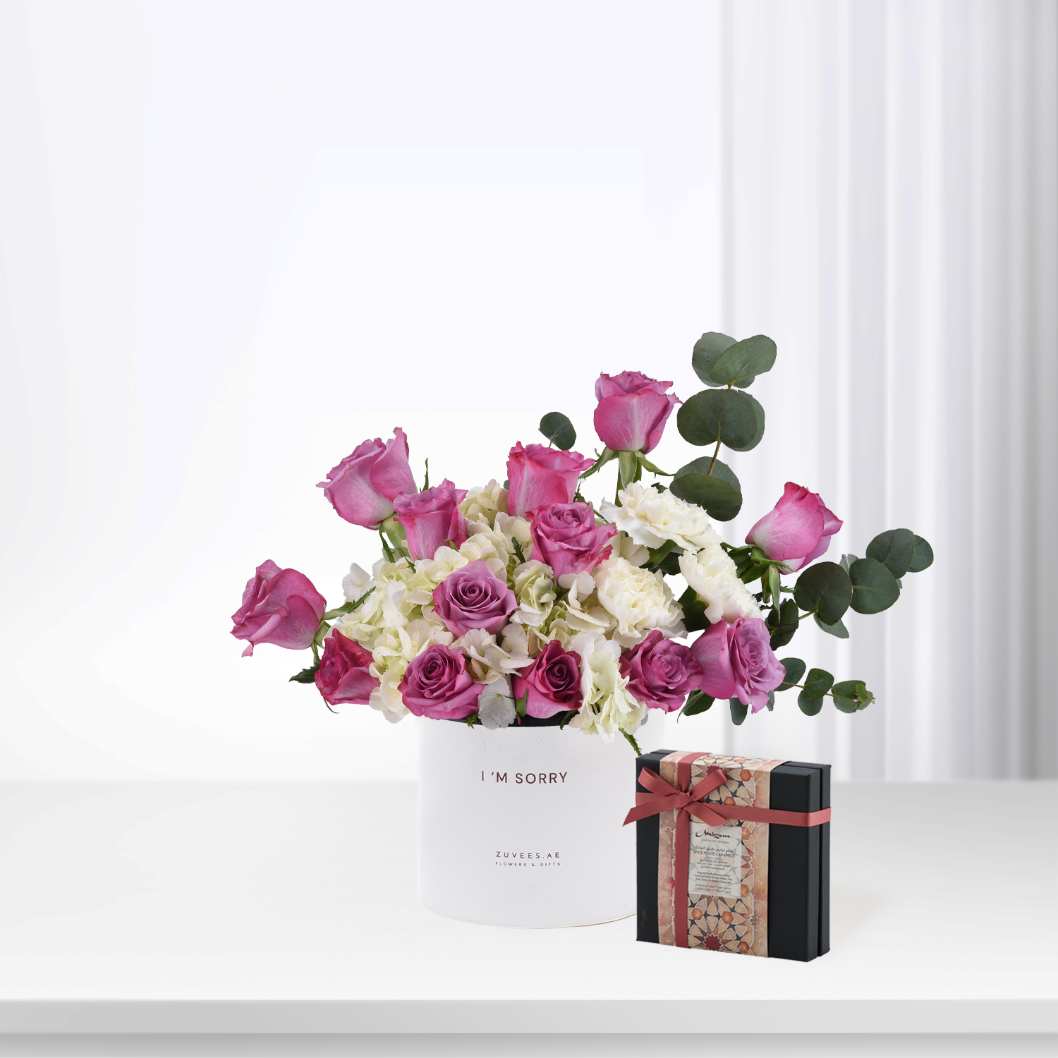 Pink roses and white hydrangeas in white box reading “I&