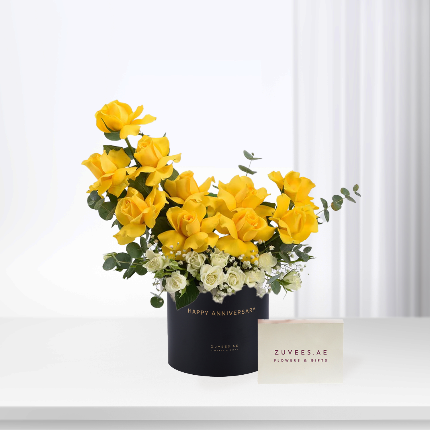 Vibrant yellow roses and white blooms in sleek black box with "Happy Anniversary" text.