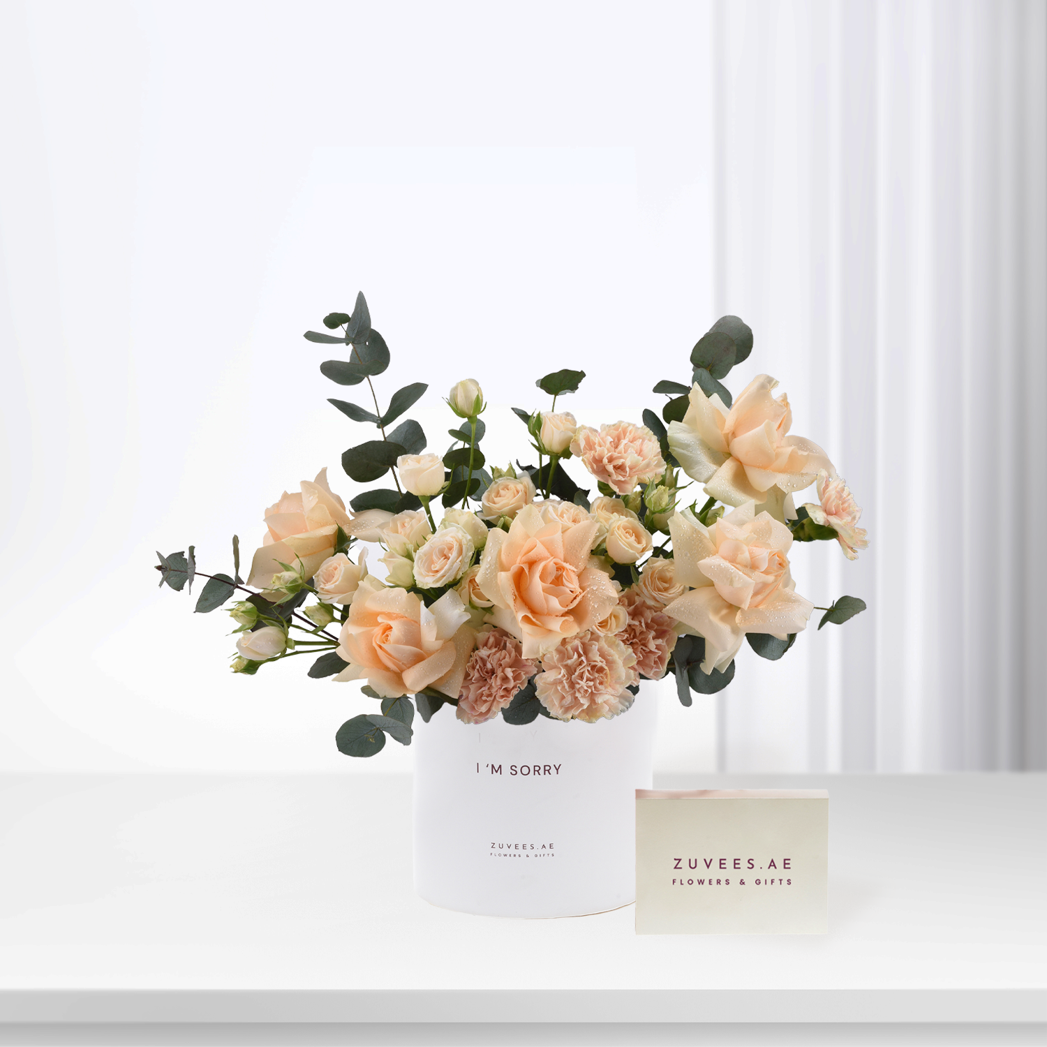 Soft peach roses and eucalyptus in white box with “I’m Sorry” message.