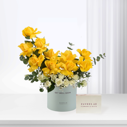Vibrant yellow roses with white accents in pastel box, "Get Well Soon" message.