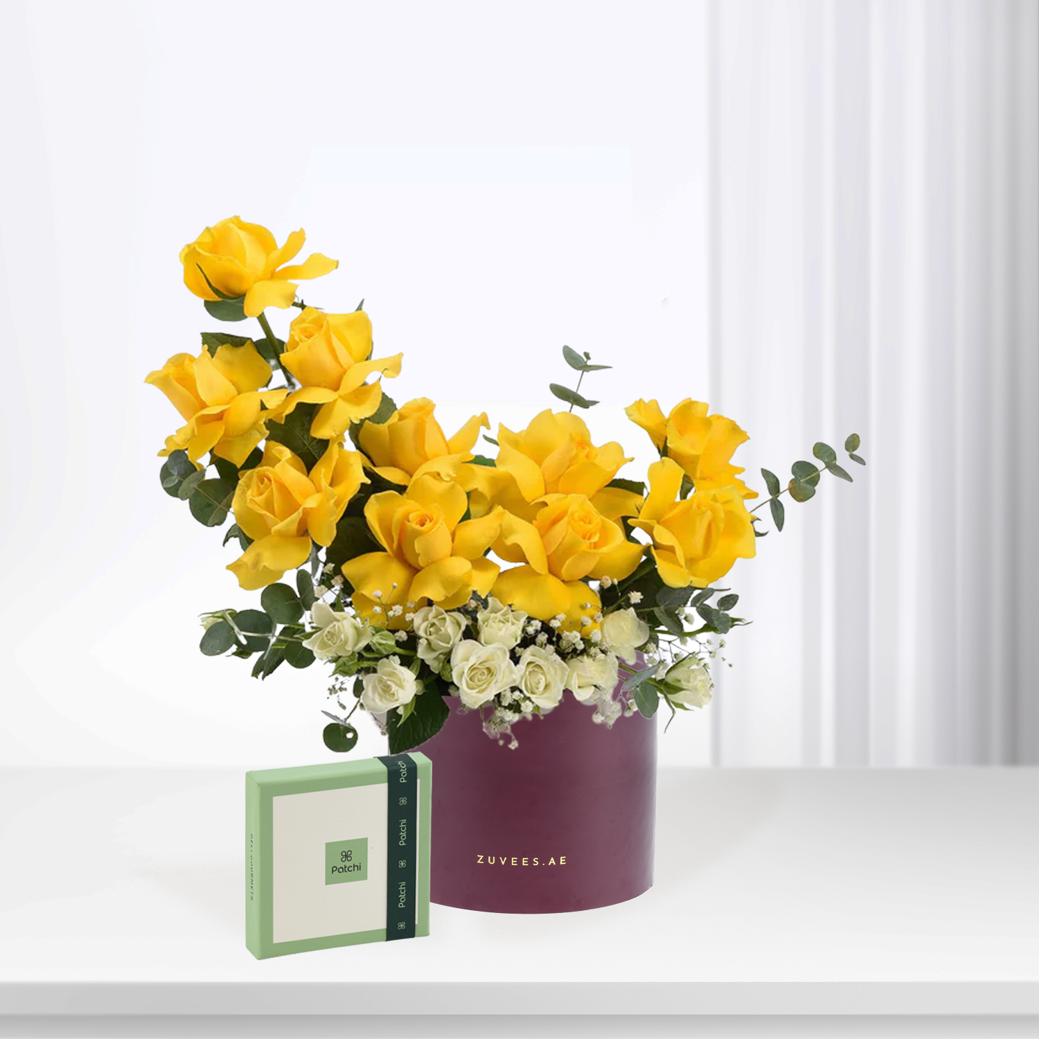 Vibrant yellow roses with white accents in purple ZUVEES.AE box, paired with Patchi chocolate gift.