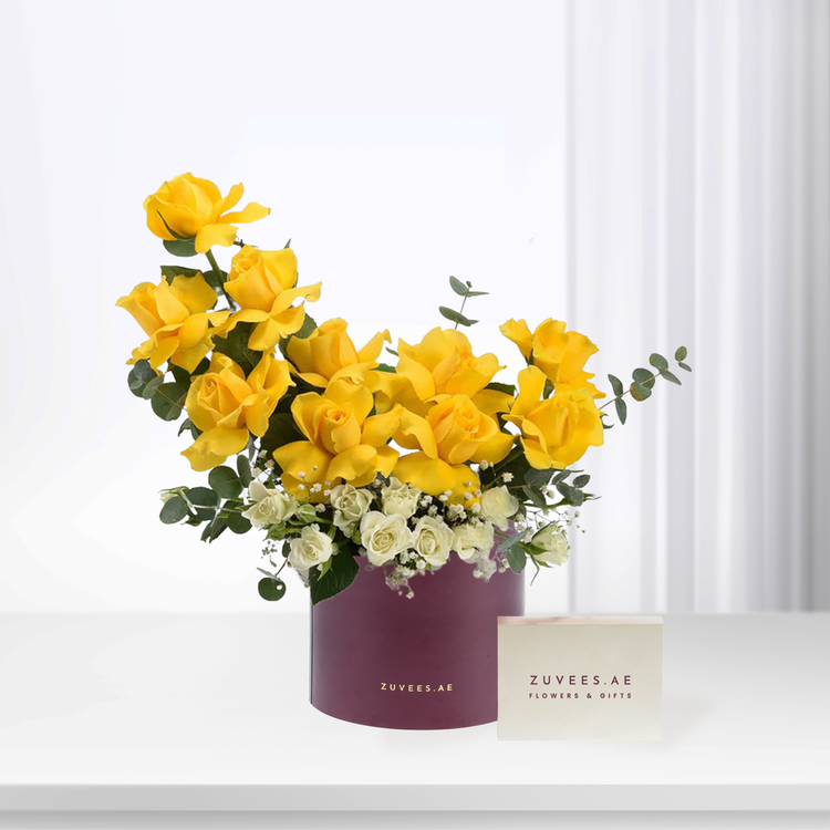Vibrant yellow roses and white blooms in deep purple box, elegant gift presentation.