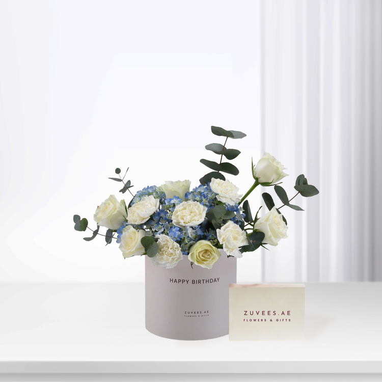 Elegant white roses and blue hydrangeas in minimalist gray birthday box.