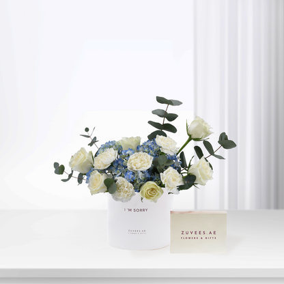 White roses and blue hydrangeas in minimalist white vase with "I&