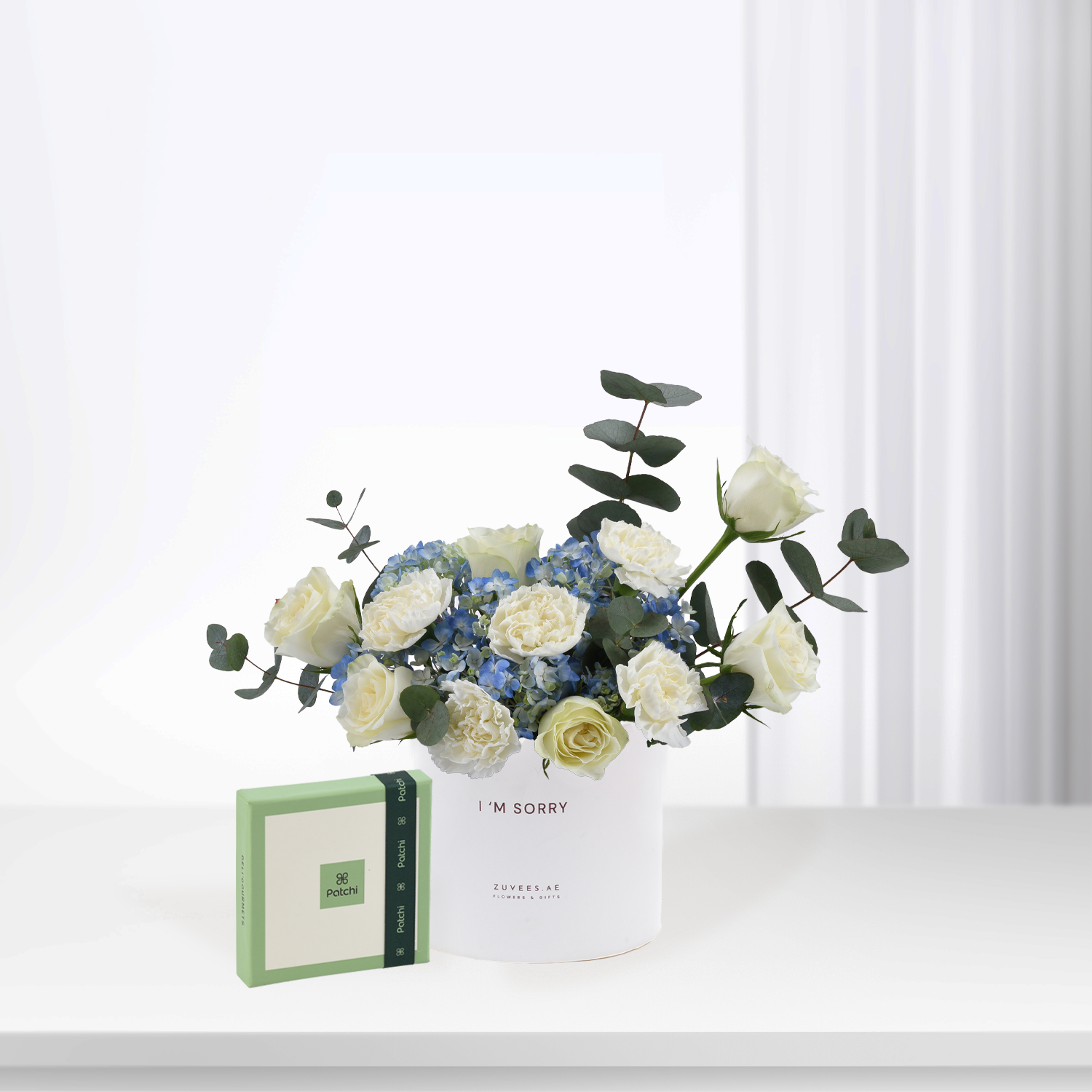 White roses and blue hydrangeas in minimalist white vase with "I&
