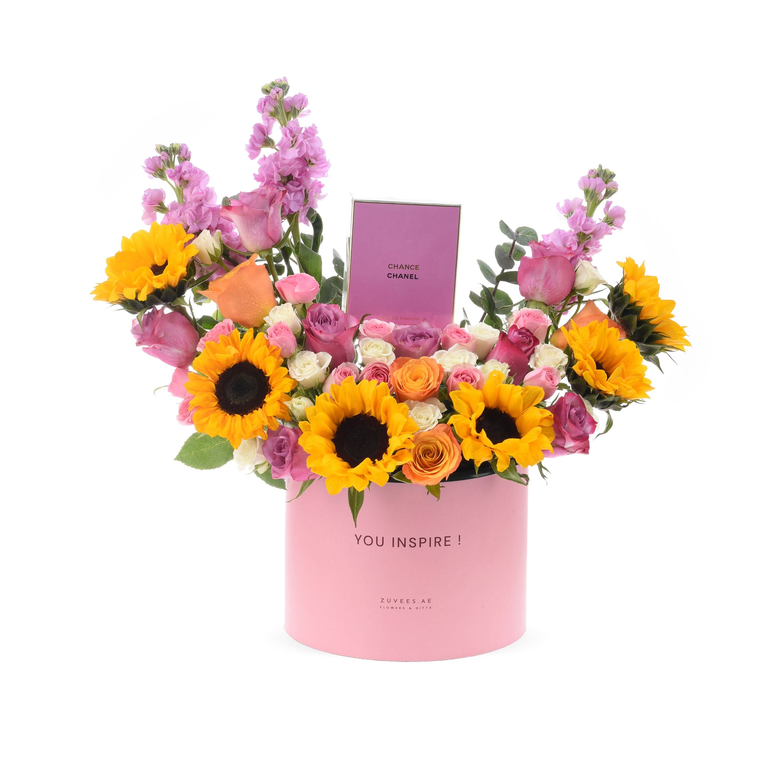 Vibrant sunflowers, pink roses, and purple blooms in pink "YOU INSPIRE!" box with Chanel perfume.