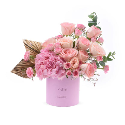 Soft pink roses and hydrangeas in lavender cylinder with gold leaf accent.