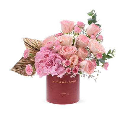 Pink roses, hydrangeas in deep red box with gold text "IN MY HEART... ALWAYS".