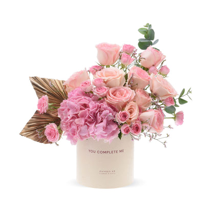 Pink roses, hydrangeas, eucalyptus in cream box with “You Complete Me” text, gold accents.