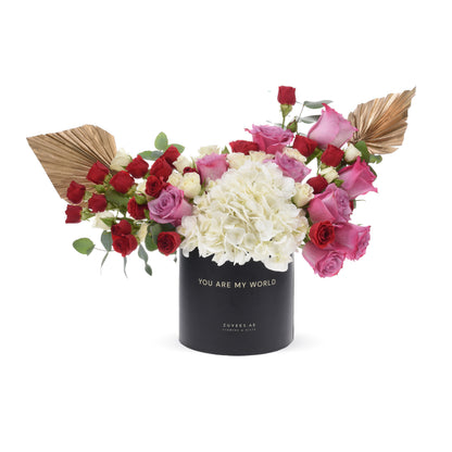 Black cylindrical box with "You Are My World" text, holding red, pink, and white roses with gold leaf accents.