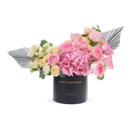Elegant pink roses and hydrangeas in black box with "Happy Anniversary" gold text.
