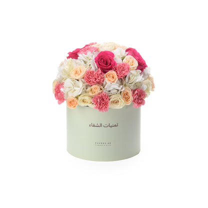 Pastel mint box overflowing with vibrant pink, peach, and white roses and carnations.
