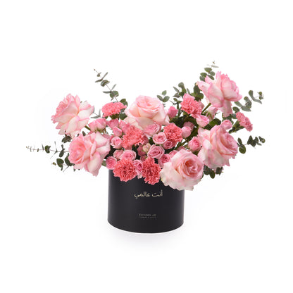 Elegant pink roses and carnations in sleek black box with Arabic script.