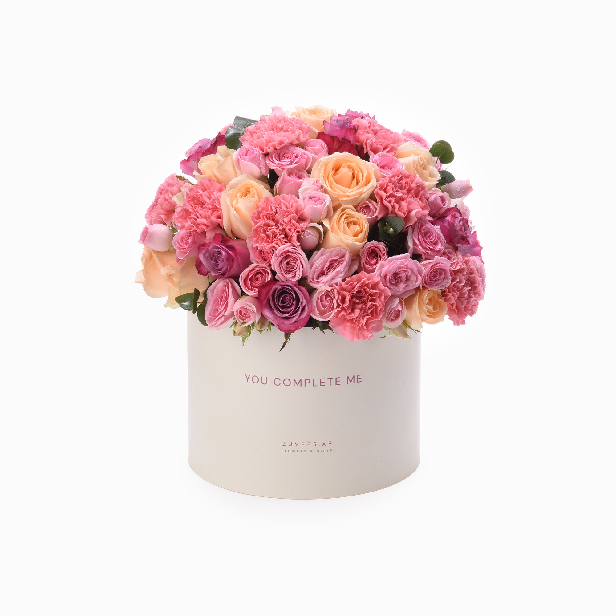 Pastel pink and peach roses and carnations in a white box reading "You Complete Me".
