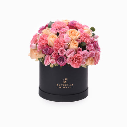 Luxurious pink rose and carnation bouquet in matte black box with gold logo.