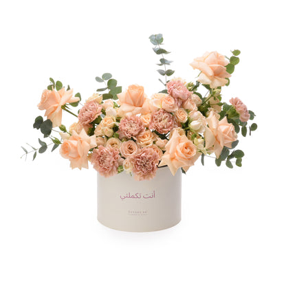 Soft peach roses and carnations in white box with Arabic message.
