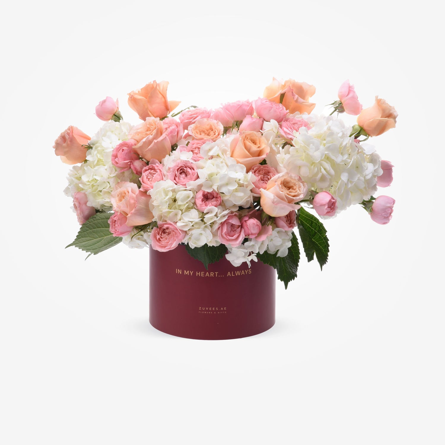 Soft pink roses and white hydrangeas in burgundy box with gold text.