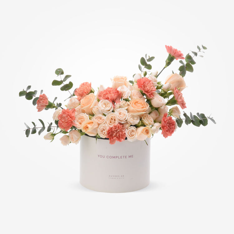 Soft peach roses and carnations in white box with "You Complete Me" text.